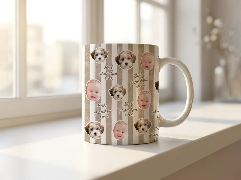 May include: A white ceramic mug with a handle, decorated with a repeating pattern of baby faces, puppy faces, and the text "Best grandpa ever" on a striped background. The mug is sitting on a white surface.