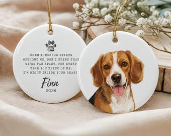 May include: Two round white ceramic ornaments with gold hanging strings. One features a brown and white beagle portrait. The other displays a black paw print, the name Finn, the year 2026, and the text: When tomorrow starts without me, don't think that we're far apart, for every time you think of me, I'm right inside your heart.