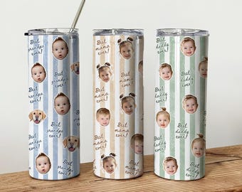 May include: Three cylindrical metal tumblers with lids and a straw. Each features vertical stripes in blue, tan, or green, printed with repeating faces of children and dogs, alongside the text Best grandpa ever, Best mama ever, or Best daddy ever.