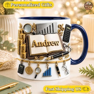 Può includere: Una tazza in ceramica bianca con interno e manico blu scuro, caratterizzata da un design 3D che raffigura un libro aperto con il nome Andrew in lettere dorate, pile di monete d'oro, una lente d'ingrandimento, una calcolatrice, una penna e un grafico.