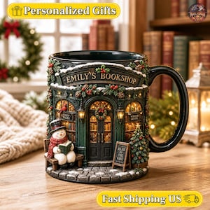 Könnte beinhalten: Ein dunkelgrüner Keramikbecher in Form einer Buchhandlung mit dem Schriftzug EMILY'S BOOKSHOP über der Tür. Ein Schneemann mit Zylinder und rotem Schal sitzt auf einer Bank und liest ein Buch. Der Becher ist weihnachtlich dekoriert.
