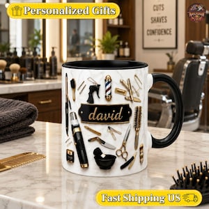 May include: A white ceramic mug with a black handle and interior, featuring a marble pattern background. The mug displays various barber tools including scissors, combs, brushes, and a barber pole, with the name david in gold script on a black plaque.
