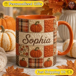 May include: A ceramic mug featuring a quilted patchwork pattern in shades of orange, brown, and cream. The design includes illustrations of pumpkins and floral motifs. The name Sophia is printed in a dark brown script font on the center panel.