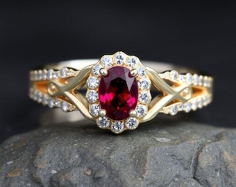 May include: A gold ring with a red oval gemstone surrounded by smaller white gemstones. The ring has a delicate, intricate design with two bands that intertwine.