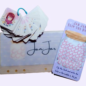 Könnte beinhalten: Ein Set quadratischer Karten an einem blauen Ring, eine rechteckige Karte mit dem Text Jan Jar Flip The Deck und eine größere rechteckige Karte mit dem Text Jan Jar. Die Karten zeigen Illustrationen eines mit rosa Kreisen gefüllten Glasgefäßes.