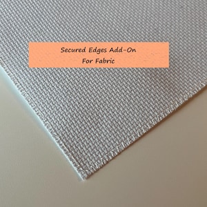 May include: A close-up of a white fabric with a stitched edge. The fabric has a subtle texture. The text "Secured Edges Add-On For Fabric" is printed on a peach-colored rectangle.