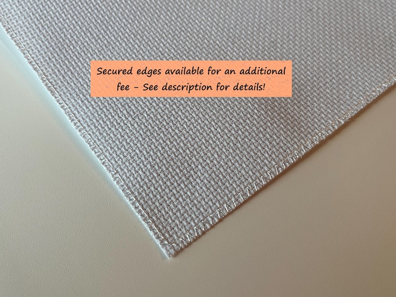 May include: Close-up of a light gray fabric with a textured weave. The edges are neatly stitched. An orange rectangle with the text "Secured edges available for an additional fee - See description for details!" is visible.