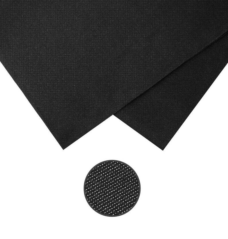 May include: Two pieces of black fabric with a textured surface are displayed, along with a small, round, black object with a dotted pattern. The fabric pieces are folded, showing their edges. The round object is a coaster.