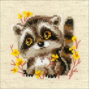 May include: A cross-stitch embroidery pattern on beige fabric featuring a small raccoon with brown and gray fur, a striped tail, and large yellow eyes. The raccoon is surrounded by small yellow flowers with thin red stems and branches.