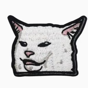 May include: Embroidered patch featuring the meme of a white cat with a smug expression. The cat's face is detailed with black eyes, a pink nose, and a slightly open mouth. The patch has a black border, suitable for application on clothing or accessories.