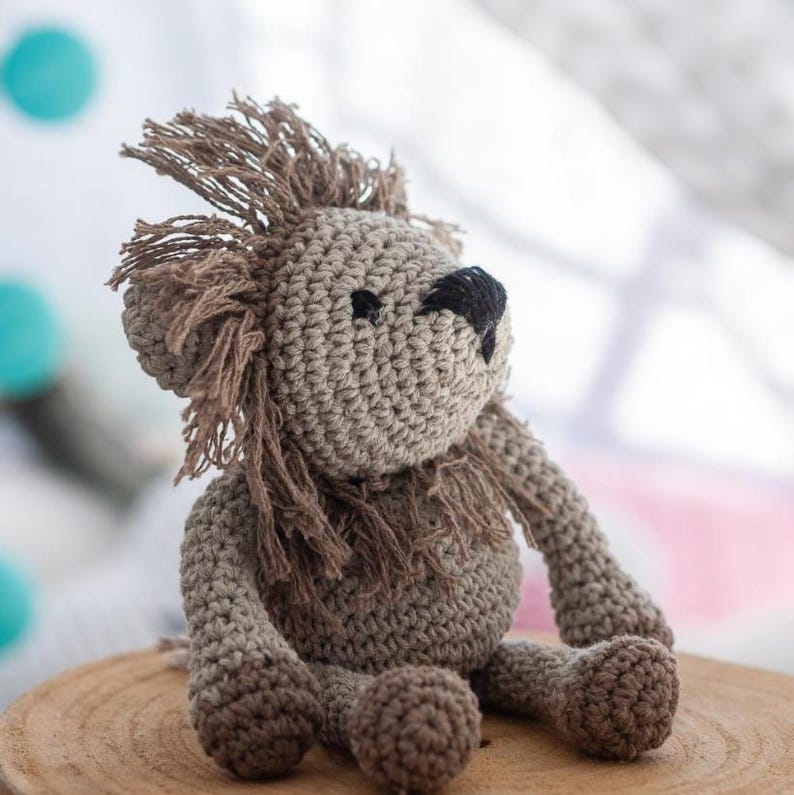 Puede incluir: Un le&oacute;n de peluche tejido a crochet en color marr&oacute;n y beige. El le&oacute;n tiene la nariz negra y una melena esponjosa.