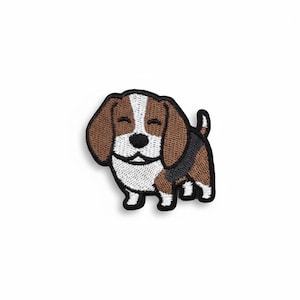 May include: Embroidered patch of a smiling beagle dog. The patch features a black outline with brown, white, and black details. The dog has floppy ears, a black nose, and a short tail. The patch is designed to be ironed on or sewn onto fabric.