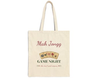 May include: A beige canvas tote bag featuring the text Mah Jongg in red, followed by an illustration of five Mah Jongg tiles, the text GAME NIGHT in dark green, and the text tiles, tea & good company in a smaller red font.