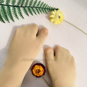 May include: A pair of beige toe socks with a split toe design. The socks are made of a thin, sheer material and are lying flat on a white surface.