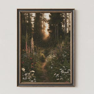 May include: A framed wall art print depicting a narrow dirt path winding through a dense forest at sunset. Tall pink foxgloves, white daisies, and green ferns line the trail, while golden light filters through the trees with floating light particles.