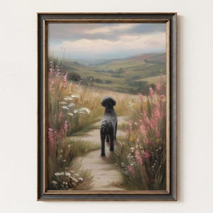 May include: A framed wall art print depicting a black dog standing on a dirt path in a grassy meadow. The scene features tall wildflowers in shades of pink and white, rolling green hills in the distance, and a cloudy sky, all enclosed in a dark frame.