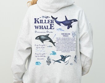 May include: Light gray hoodie featuring a graphic of a killer whale with the text "KILLER WHALE Orcinus Orca". The design includes illustrations of whales, fish, and aquatic plants. The hoodie also includes the text "Ang Length - Up to 32 ft" and "Ang Weight - Up to 8,800 lbs (female)".