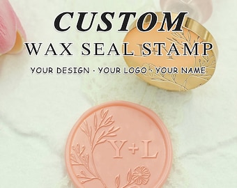 May include: A gold wax seal stamp with a floral design and the initials "Y+L". The stamp is used to create a wax seal with the same design. The wax seal is pink and has a floral design.
