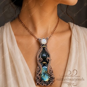 May include: A copper wire-wrapped pendant necklace featuring a round moonstone at the top, a dark oval gemstone in the centre, and a large, iridescent blue labradorite at the base, all suspended from a matching copper chain link necklace.