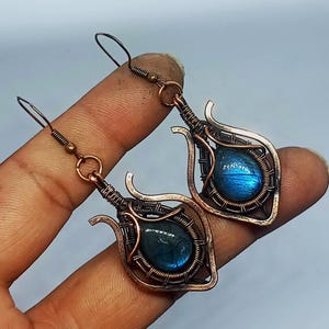 Könnte beinhalten: Ein Paar Ohrringe aus kupferdraht mit blauen Labradorit-Edelsteinen. Die Ohrringe sind tropfenförmig mit einem filigranen Drahtdesign.