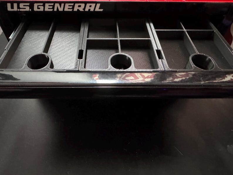 Puede incluir: Un caj&oacute;n negro con un inserto gris texturizado y compartimentado. El caj&oacute;n est&aacute; abierto y el inserto es visible. El caj&oacute;n est&aacute; etiquetado con "U.S. GENERAL" en letras blancas.