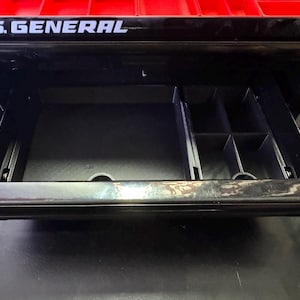 Puede incluir: Una caja de herramientas negra con un caj&oacute;n abierto, que revela un organizador compartimentado. La caja de herramientas tiene una tapa roja con las palabras "U.S. GENERAL" impresas en blanco.