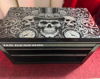 May include: Black tool chest with three drawers. The top is decorated with a skull wearing a top hat, surrounded by gears and clocks. The text "U.S. GENERAL" is printed on the front.