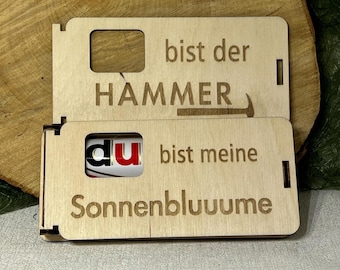 Könnte beinhalten: Zweiteilige Holzgeschenkbox mit graviertem Text. Der obere Teil lautet "bist der HAMMER" mit einer Hammergrafik. Der untere Teil lautet "du bist meine Sonnenbluume" mit einem sichtbaren Schokoriegel.