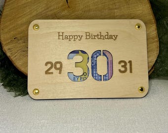 May include: A wooden card with the words "Happy Birthday" and the numbers 29, 30, and 31. The number 30 has a cutout that reveals a Euro banknote.