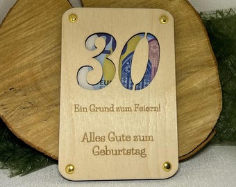 May include: A wooden card with a cutout of the number 30. The card has gold accents and the text "Ein Grund zum Feiern! Alles Gute zum Geburtstag".