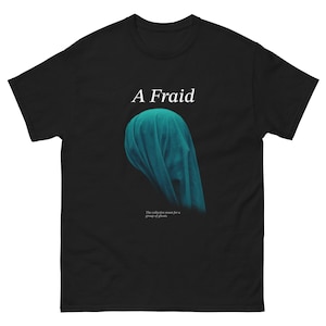 May include: Black t-shirt with the word "A Fraid" in white text above a teal draped fabric design. Below the design is the text "The collective noun for a group of ghosts."