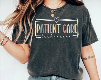 May include: A dark gray t-shirt with a white box around the text "PATIENT CARE" in colorful letters. The text "technician" is written in smaller letters below the box. A small white heart is above the box.
