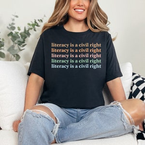 May include: A black t-shirt with the text "literacy is a civil right" repeated five times in different colours.
