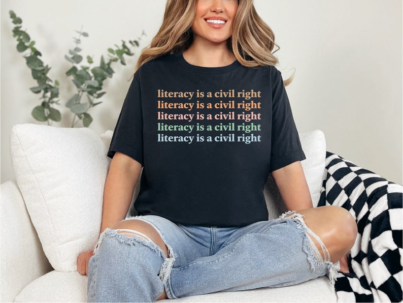 May include: A black t-shirt with the text "literacy is a civil right" repeated five times in different colours.