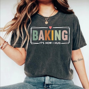 May include: A gray t-shirt with the text "Baking - It's how I hug" in a colorful box with a small red heart above the text.
