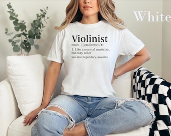 May include: A white short-sleeve t-shirt featuring black text that reads: Violinist noun. / (varəlinist)/ 1. Like a normal musician, but way cooler See also: legendary, awsome. The shirt is worn with light blue distressed denim jeans.