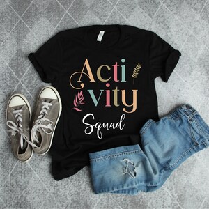 May include: Black t-shirt with the text "Activity Squad" in colorful letters with floral accents.