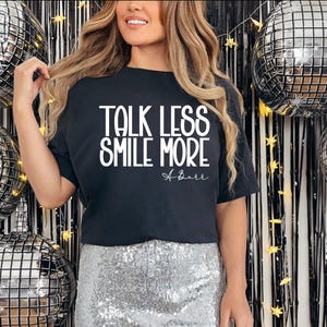 Pu&ograve; includere: T-shirt nero con la scritta bianca &laquo;TALK LESS SMILE MORE&raquo;. L'outfit comprende una gonna di paillettes argentata. Palloncini a sfera da discoteca e uno sfondo nero e argento completano il look festivo.