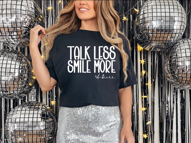 Pu&ograve; includere: T-shirt nero con la scritta bianca &laquo;TALK LESS SMILE MORE&raquo;. L'outfit comprende una gonna di paillettes argentata. Palloncini a sfera da discoteca e uno sfondo nero e argento completano il look festivo.