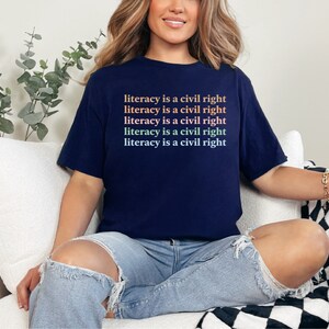 May include: A navy blue t-shirt with the text "literacy is a civil right" repeated five times in a gradient of pink, orange, and green.