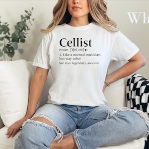 May include: A white short-sleeve t-shirt featuring black text that reads Cellist, noun, [tʃel.ɪst], 1. Like a normal musician, but way cooler, See also: legendary, awesome. The shirt has a crew neckline and a standard fit.