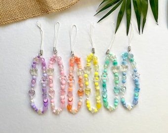 May include: Six colorful phone charms with different colored beads, including purple, pink, orange, yellow, blue, and light blue. Each charm features a string of beads with butterfly and heart shapes.