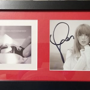 May include: Framed black and white photograph with a red mount. The frame holds two images: one of an album cover and the other of a person with an autograph. The album cover has text. The other image is a portrait of a person.