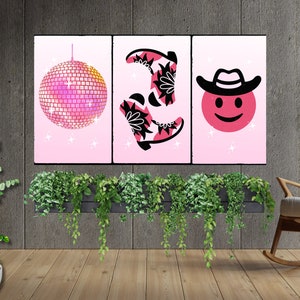 May include: Three pink framed prints featuring a disco ball, a pair of pink and black cowboy boots, and a pink smiley face wearing a cowboy hat.