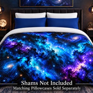 May include: A duvet cover featuring a vibrant galaxy print with swirling clouds of deep blue, purple, and bright cyan nebula gas, scattered with numerous white stars and spiral galaxies. The bedding is layered with solid blue and white pillows.