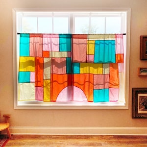May include: A pair of window curtains featuring a patchwork design of translucent fabric panels in vibrant shades of turquoise, yellow, orange, pink, and red. The rectangular and arched segments are stitched together, allowing light to filter through.