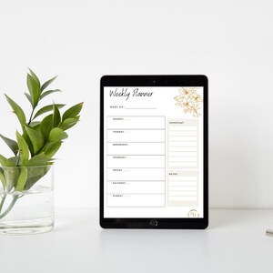 May include: A black tablet displaying a weekly planner template with the text "Weekly Planner." The planner includes sections for each day of the week, "Important" notes, and a floral design in the upper right corner.