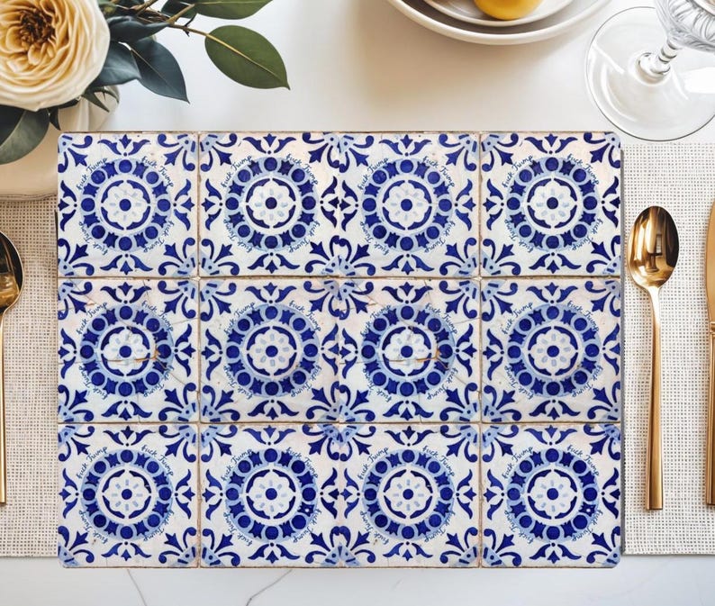 Pu&ograve; includere: Un sottopentola rettangolare composto da dodici piastrelle quadrate. Ogni piastrella presenta un motivo floreale blu e bianco con un medaglione centrale e volute. Il sottopentola &egrave; posto su una superficie bianca, con posate dorate e un fiore.