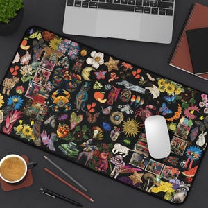 May include: A rectangular black mousepad featuring a collage of colorful illustrations. The design includes flowers, animals, stamps, and celestial elements. A white mouse and a laptop are on the mousepad.