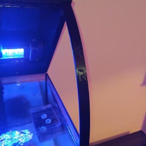 Könnte beinhalten: Ein schwarzes Aquarium mit einem blauen Licht und einem schwarzen Deckel mit einem gebogenen Griff. Der Griff hat den Buchstaben "R" aufgedruckt.